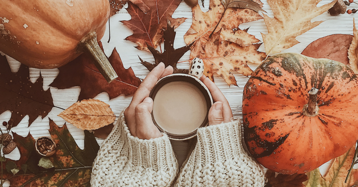 woman holding coffee with fall  leaves and pumpkins